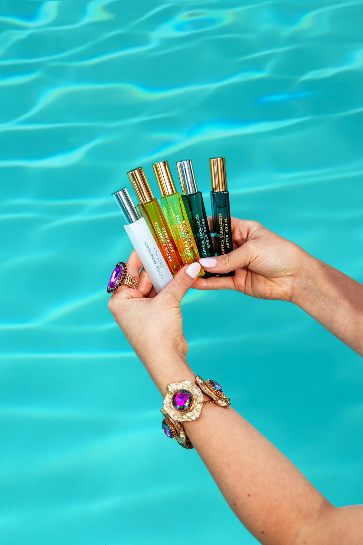 The rollerball collection fanned in hand over turquoise water.
