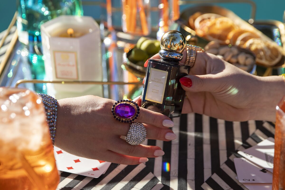 The After Hours bottle passed across the table — amethyst rings, playing cards, dusk gold.