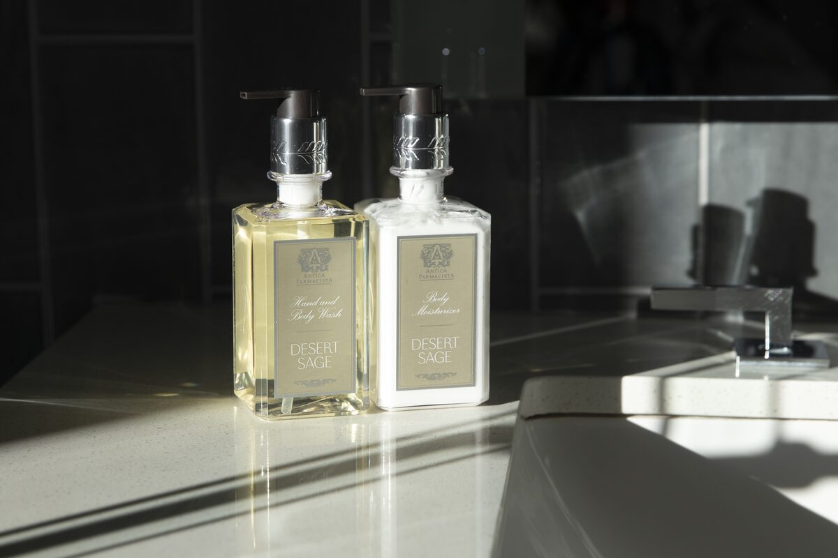 Desert Sage hand wash and body moisturiser side by side on a dark bathroom counter in raking light.