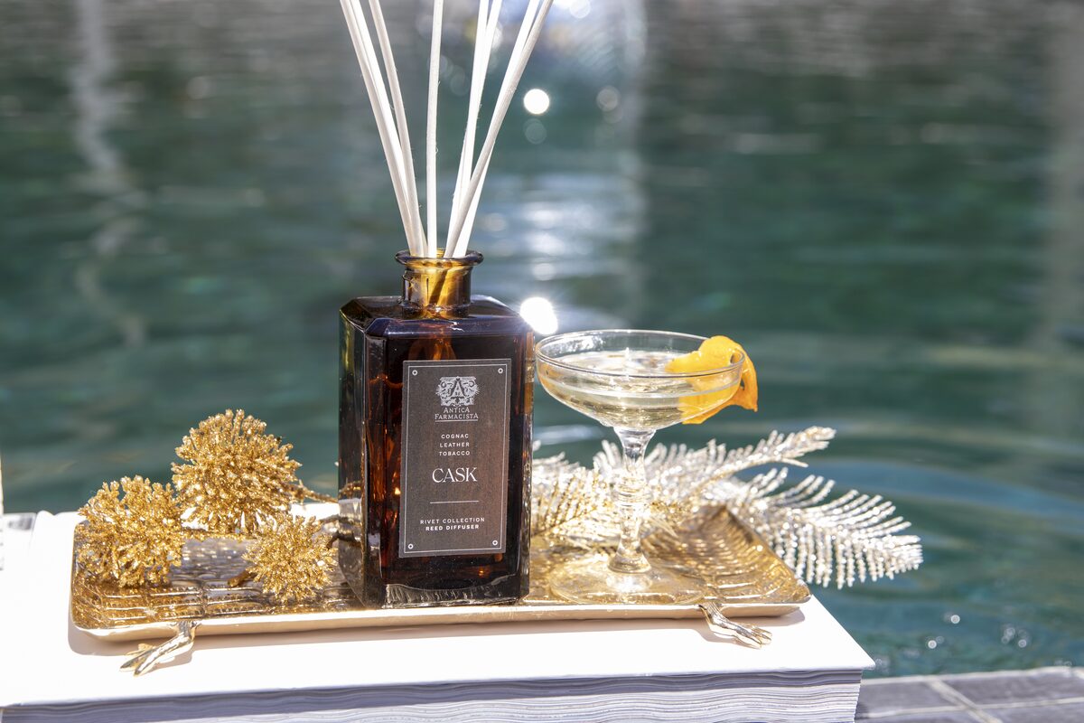 The Cask diffuser and a garnished coupe on a gold tray over turquoise pool water.