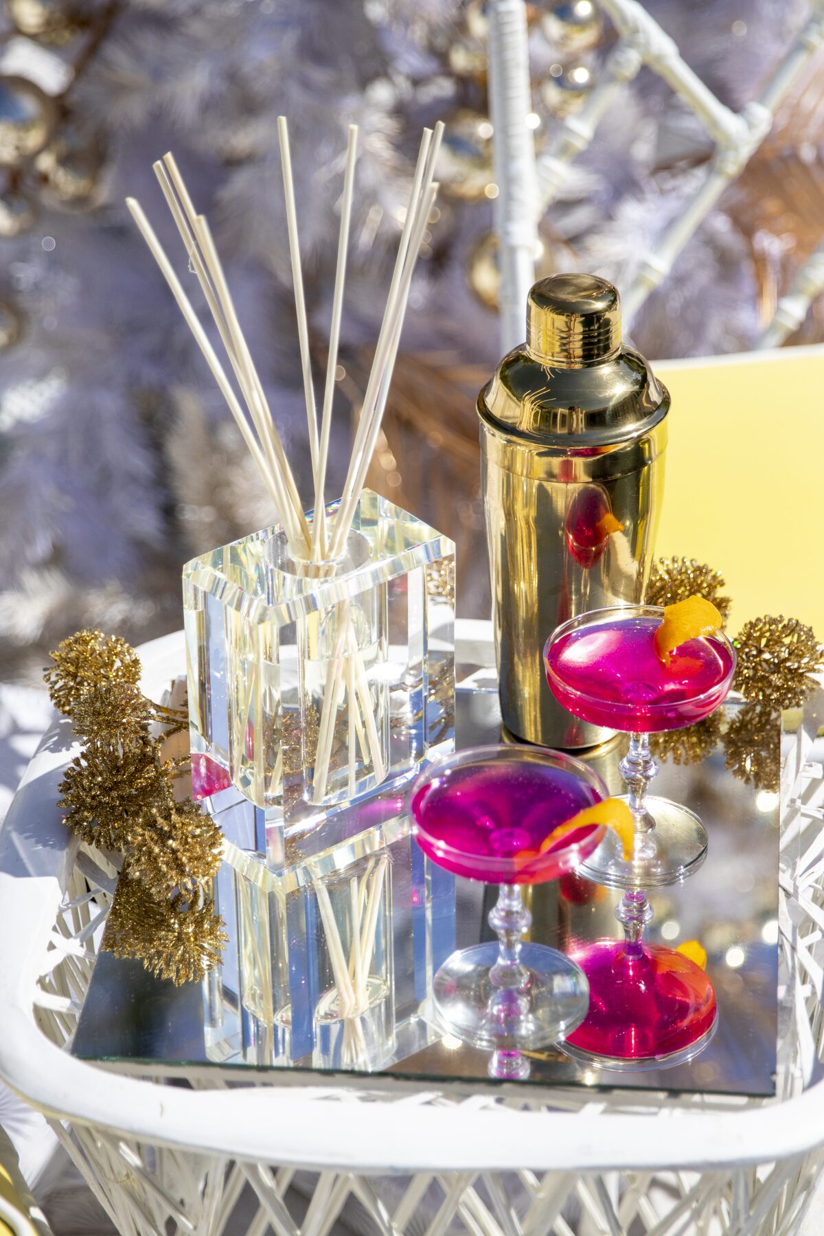 The crystal diffuser beside a gold cocktail shaker and pink cosmos at the white tree.