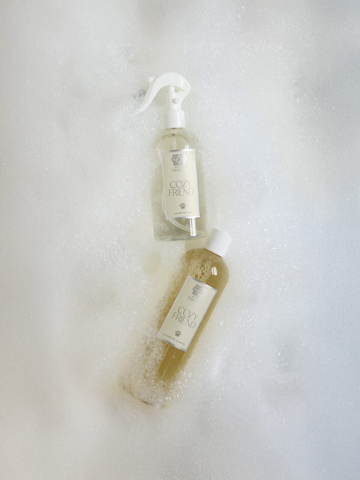 The Cozy Friend spray and wash — the pet-care companion launch — floating in bath foam, paw marks on the labels.