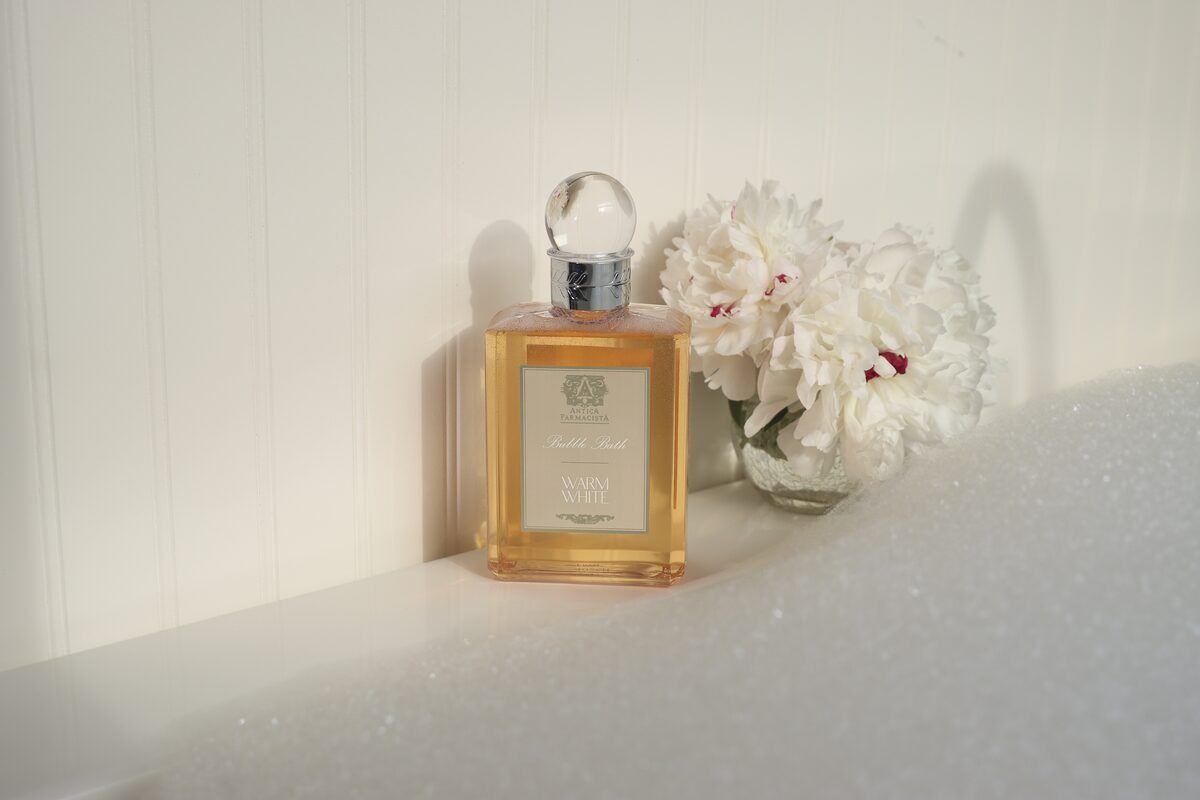 The amber wash backlit on the tub’s edge, peonies catching the same light.