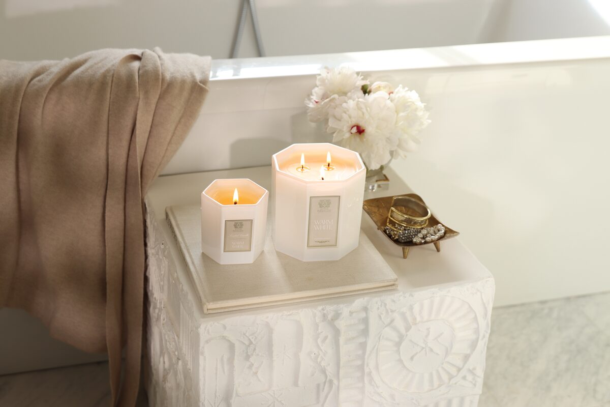 Two Warm White candles burning on the carved plaster table, a gold trinket dish between them.