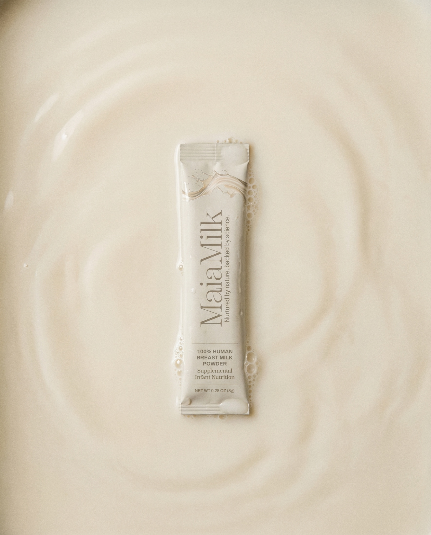 A single MaiaMilk packet rests in a quiet field of milk and small bubbles.